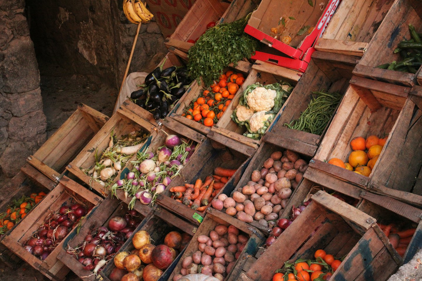 Frutas y verduras frescas expuestas en cajas de madera de mercado.